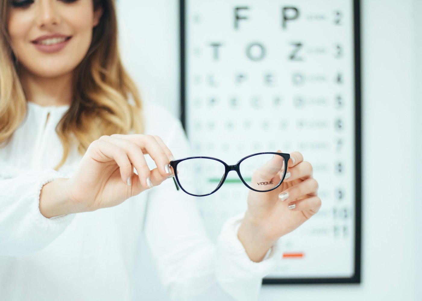 Optikė laiko akinius su lęšiais pagal receptą prie regos patikros lentelės
